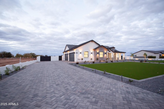 modern inspired farmhouse featuring a front yard, decorative driveway, fence, and a garage