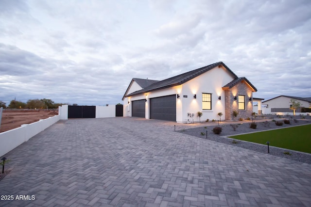 view of home's exterior featuring decorative driveway, fence, a garage, and stucco siding