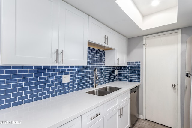 kitchen featuring stainless steel dishwasher, sink, decorative backsplash, and white cabinets