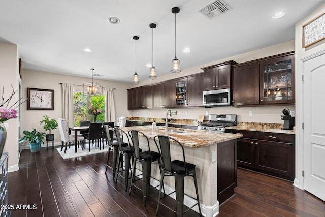3766 E Ringtail Way, Phoenix, AZ 85050 - kitchen featuring appliances with stainless steel finishes, dark wood-type flooring, dark brown cabinets, a breakfast bar area, and light stone counters