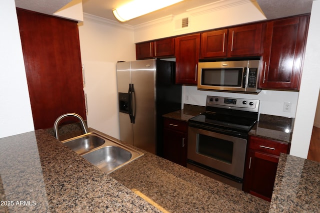 2025 E Campbell Ave Unit 120, Phoenix, AZ 85016 - kitchen with appliances with stainless steel finishes, reddish brown cabinets, ornamental molding, and dark stone counters