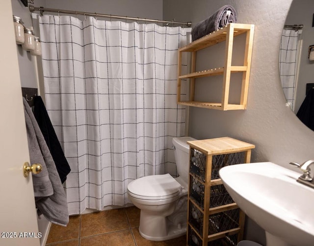 bathroom with tile patterned flooring, sink, curtained shower, and toilet