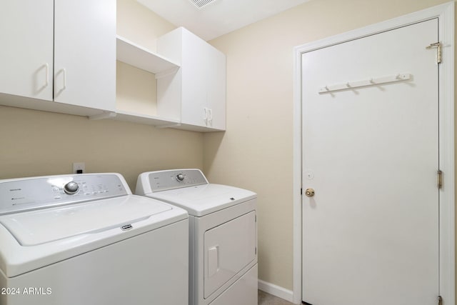 clothes washing area with cabinets and washing machine and dryer