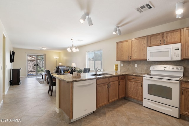 kitchen featuring white appliances, backsplash, sink, kitchen peninsula, and a chandelier