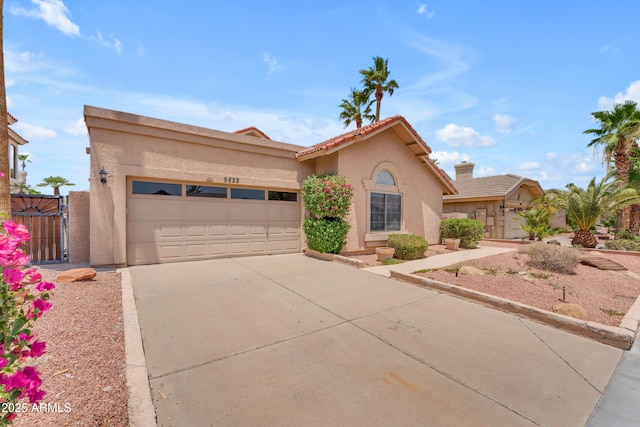 5822 W Abraham Ln, Glendale, AZ 85308 - mediterranean / spanish-style home with stucco siding, concrete driveway, an attached garage, a gate, and a tiled roof