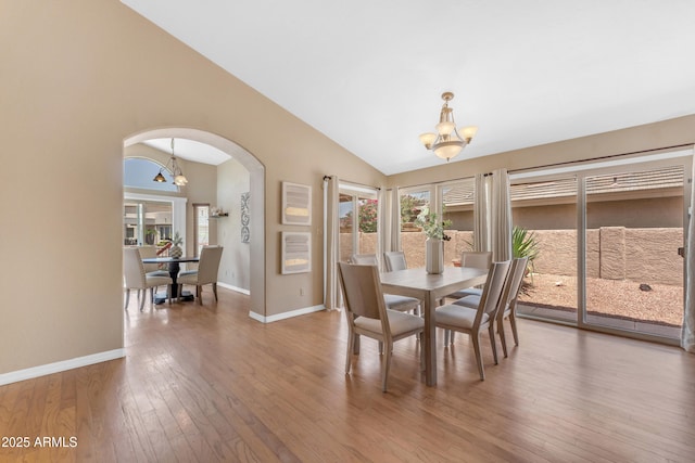 5822 W Abraham Ln, Glendale, AZ 85308 - dining room with a chandelier, lofted ceiling, arched walkways, wood-type flooring, and plenty of natural light