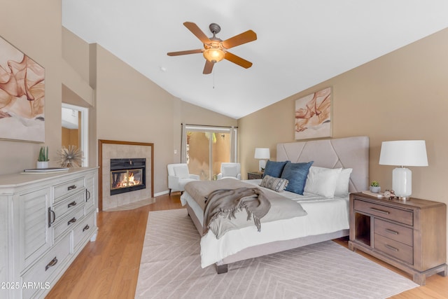 5822 W Abraham Ln, Glendale, AZ 85308 - bedroom featuring light wood-style floors, a tile fireplace, lofted ceiling, and a ceiling fan