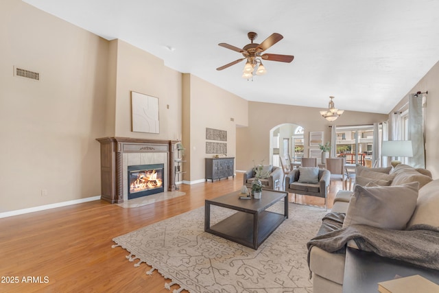 5822 W Abraham Ln, Glendale, AZ 85308 - living area featuring lofted ceiling, arched walkways, light wood-style flooring, ceiling fan, and a tile fireplace