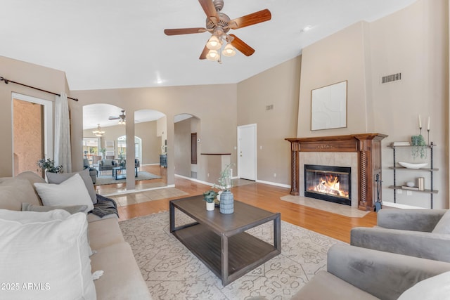 5822 W Abraham Ln, Glendale, AZ 85308 - living area featuring ceiling fan, arched walkways, light wood-style flooring, a tile fireplace, and high vaulted ceiling