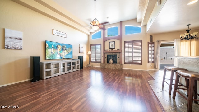 living area with beam ceiling, dark wood finished floors, a fireplace, an inviting chandelier, and baseboards