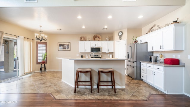 kitchen featuring light countertops, appliances with stainless steel finishes, a kitchen island with sink, and white cabinets