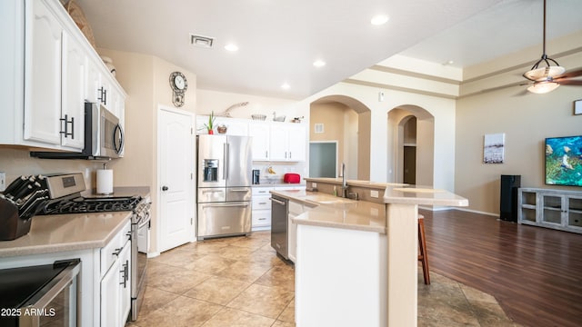 kitchen featuring stainless steel appliances, a sink, white cabinets, light countertops, and an island with sink