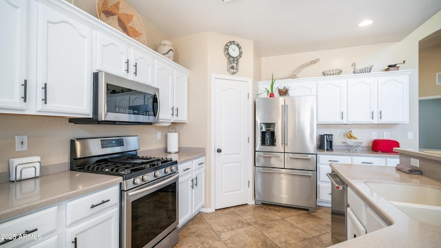 kitchen with appliances with stainless steel finishes, light countertops, white cabinets, and a sink