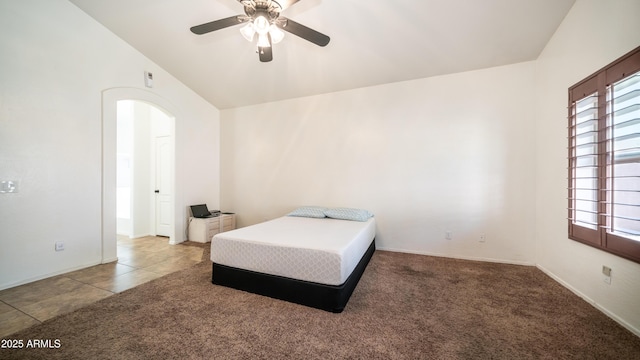 bedroom featuring arched walkways, a ceiling fan, tile patterned flooring, vaulted ceiling, and carpet floors