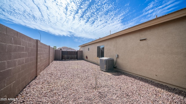 view of side of home featuring central air condition unit, a fenced backyard, and stucco siding