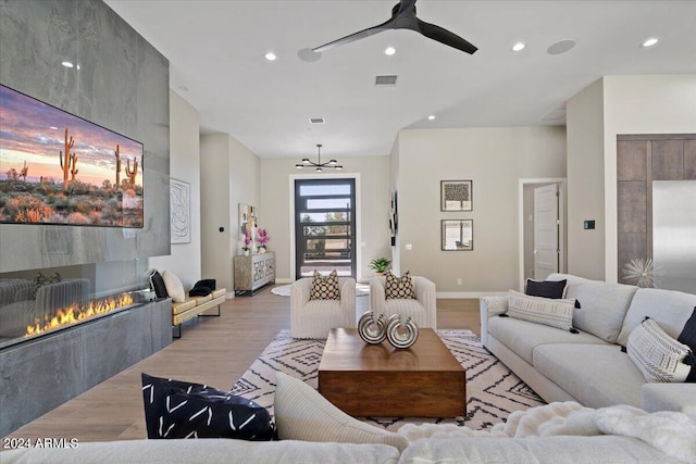 living room featuring a fireplace, light wood-type flooring, and ceiling fan