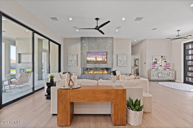 living room with light hardwood / wood-style floors, a large fireplace, and ceiling fan