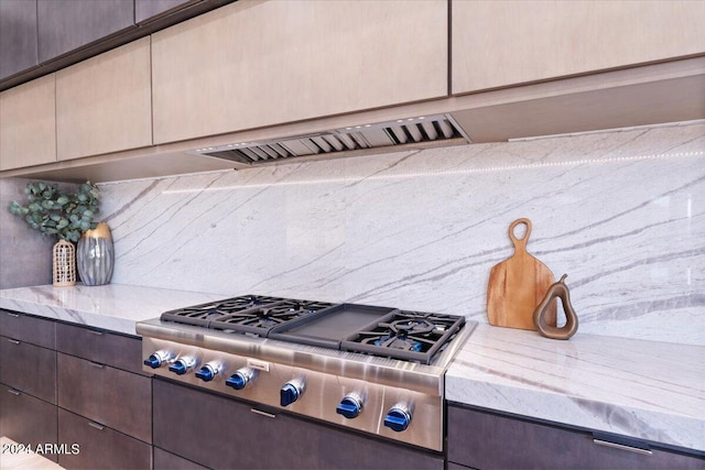 kitchen with light stone countertops, stainless steel gas cooktop, and dark brown cabinetry