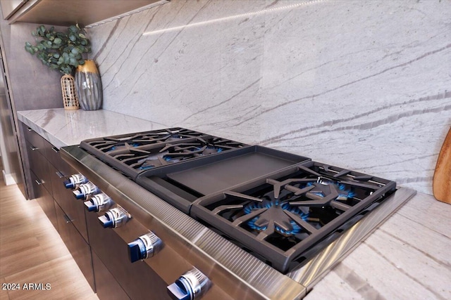 details with stainless steel range with gas stovetop, dark brown cabinets, and light wood-type flooring