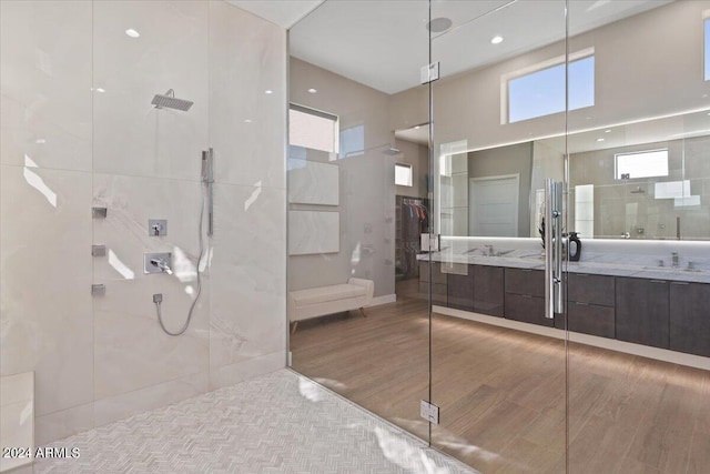 bathroom featuring vanity, hardwood / wood-style floors, a shower with shower door, and a towering ceiling