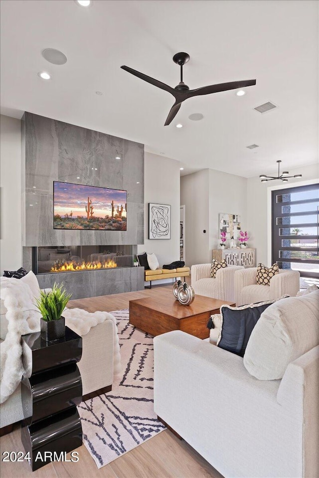 living room featuring ceiling fan, hardwood / wood-style flooring, and a fireplace