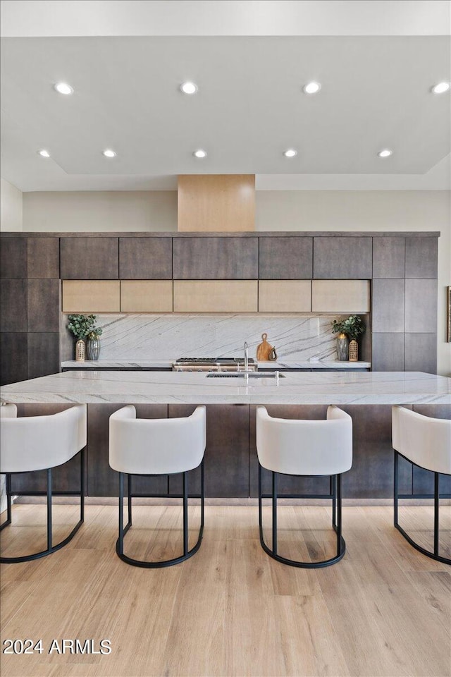 kitchen with light hardwood / wood-style flooring, sink, and a breakfast bar