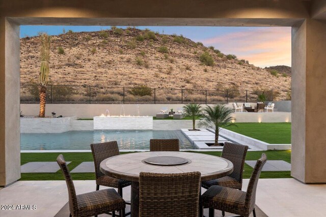 patio terrace at dusk with a mountain view and a lawn