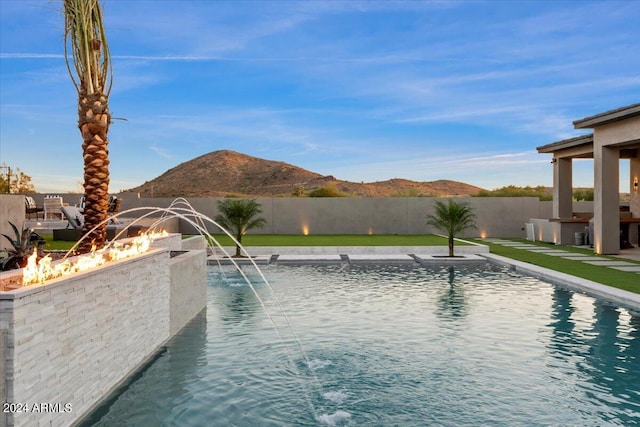 view of swimming pool with an outdoor fire pit, a mountain view, and pool water feature