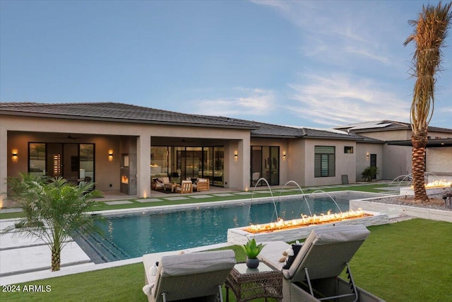 view of swimming pool featuring a patio, pool water feature, an outdoor living space with a fire pit, and a yard