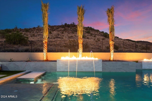 pool at dusk featuring pool water feature