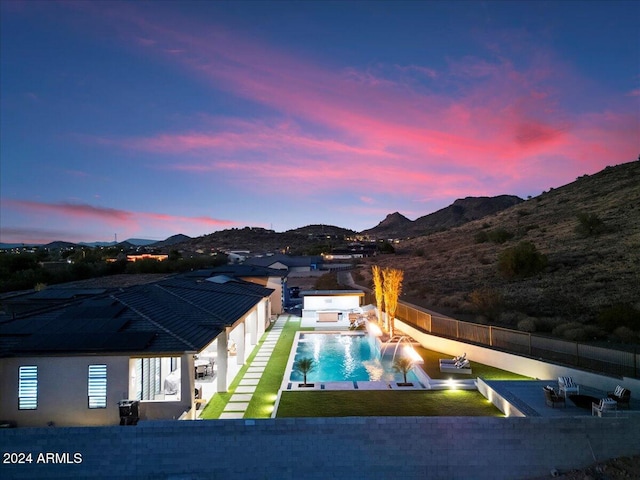 pool at dusk featuring a patio, a mountain view, pool water feature, and a jacuzzi