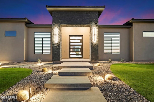 exterior entry at dusk with a lawn