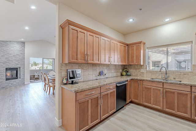 kitchen featuring a large fireplace, sink, backsplash, light hardwood / wood-style floors, and vaulted ceiling