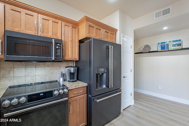 kitchen with tasteful backsplash, light stone countertops, light hardwood / wood-style flooring, and stainless steel appliances