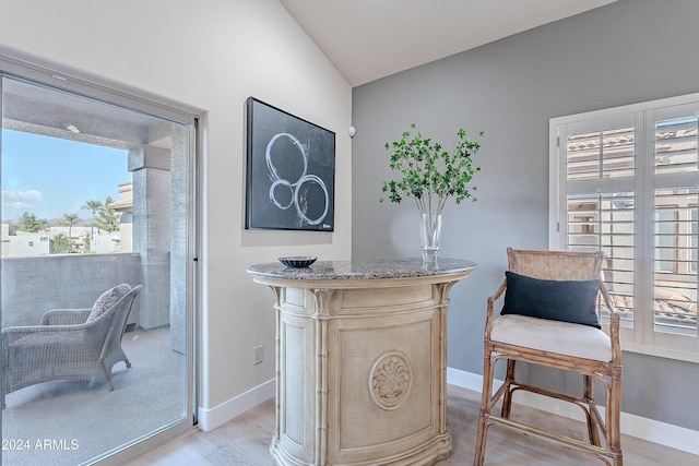 living area featuring a wealth of natural light, vaulted ceiling, and light wood-type flooring