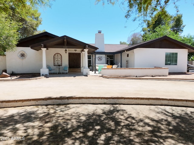 rear view of property with a chimney and stucco siding