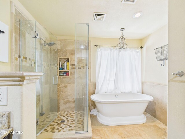 full bathroom with a shower stall, a freestanding tub, a wainscoted wall, tile walls, and tile patterned flooring