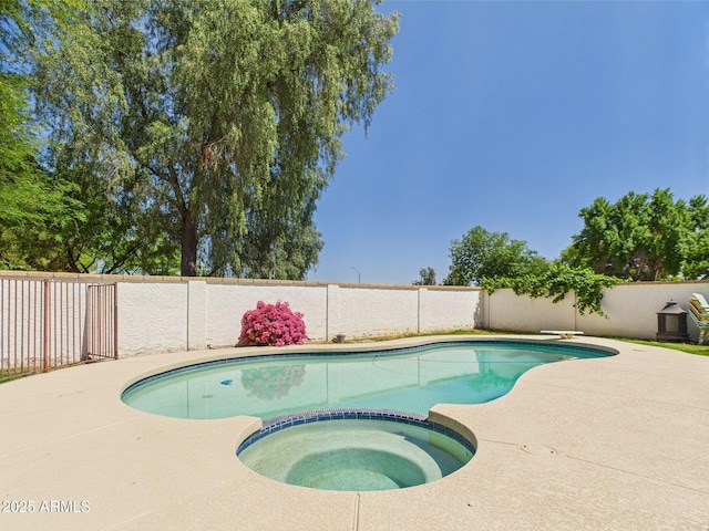 view of swimming pool with a fenced backyard, a pool with connected hot tub, and a patio area