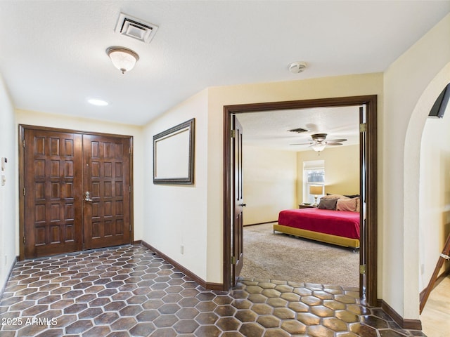 carpeted foyer with arched walkways, baseboards, and a ceiling fan