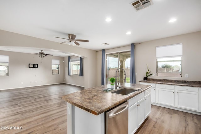 kitchen featuring visible vents, a center island with sink, dishwasher, light wood-style flooring, and a sink