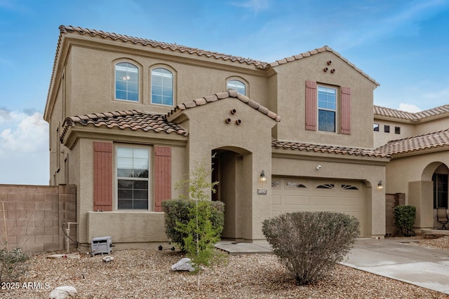 mediterranean / spanish house featuring stucco siding, a garage, and driveway