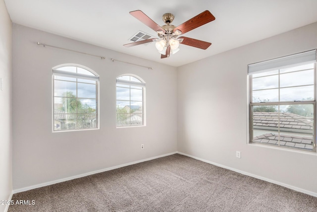 carpeted spare room featuring visible vents, baseboards, and ceiling fan