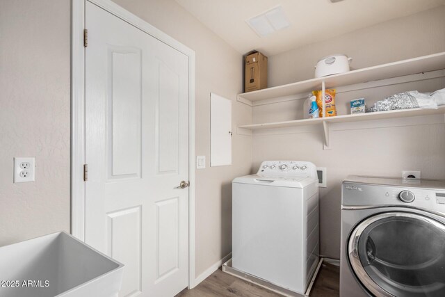 laundry area with baseboards, laundry area, wood finished floors, independent washer and dryer, and a sink