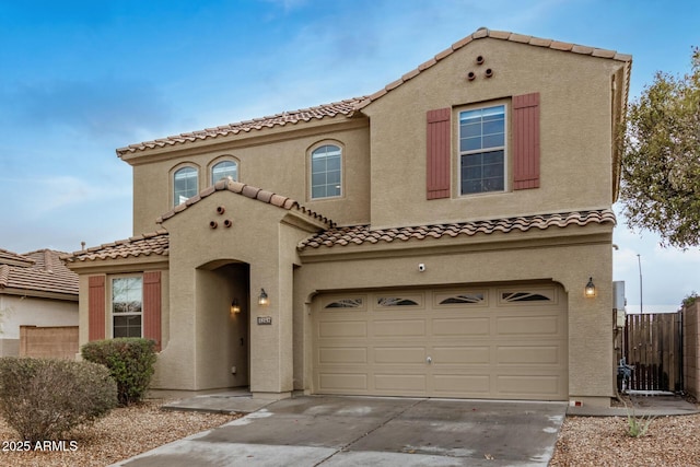 mediterranean / spanish-style home with stucco siding, driveway, an attached garage, and fence