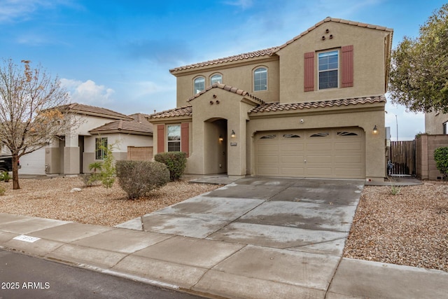 mediterranean / spanish home with stucco siding, a garage, driveway, and fence