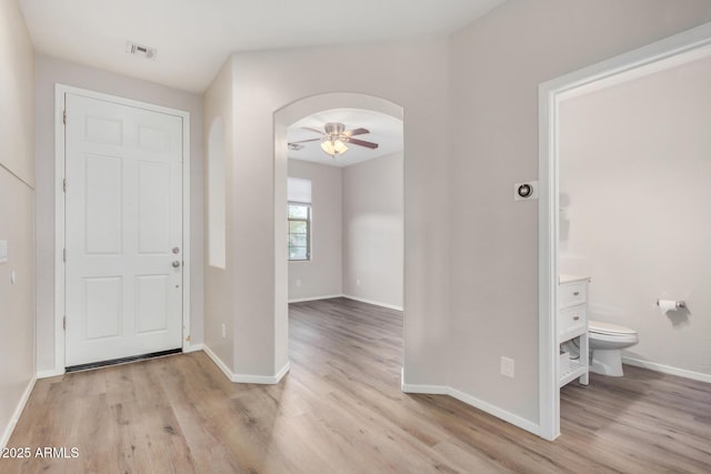 foyer featuring arched walkways, visible vents, light wood finished floors, and baseboards