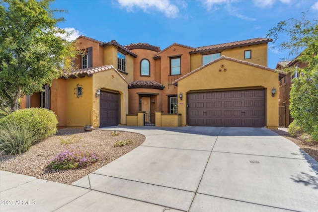 mediterranean / spanish home with driveway, an attached garage, a tiled roof, and stucco siding