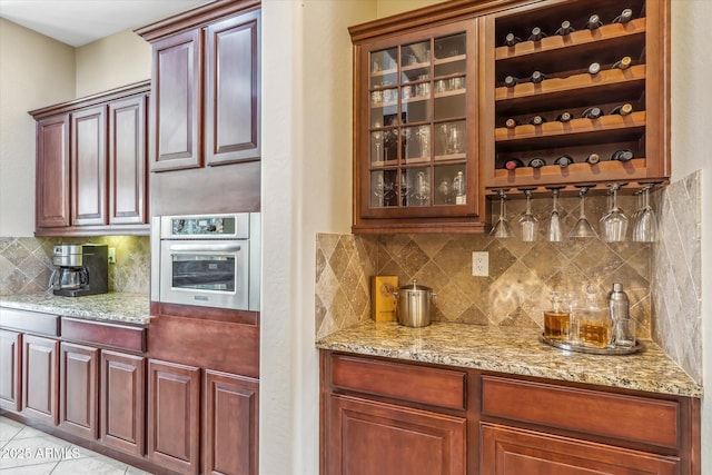 bar with light tile patterned floors, tasteful backsplash, and stainless steel oven