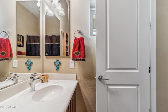 bathroom with a textured wall and vanity