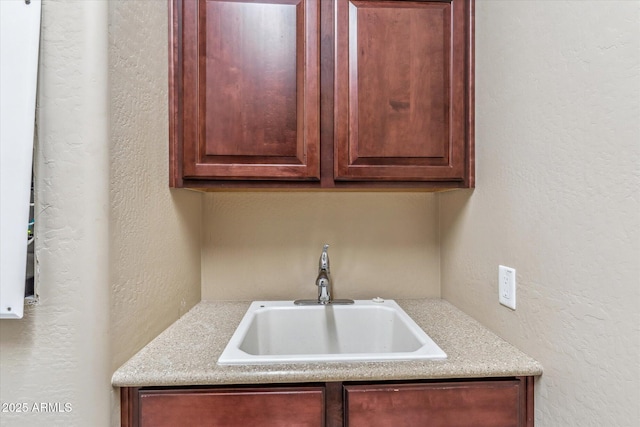 kitchen with light countertops, a sink, and a textured wall